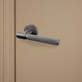 Gun Metal PVD gecoate Cosenza deurklink met gekartelde structuur op beige binnendeur, rechteraanzicht