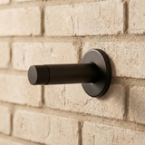 Gemonteerde zwarte deurstopper op een bakstenen muur